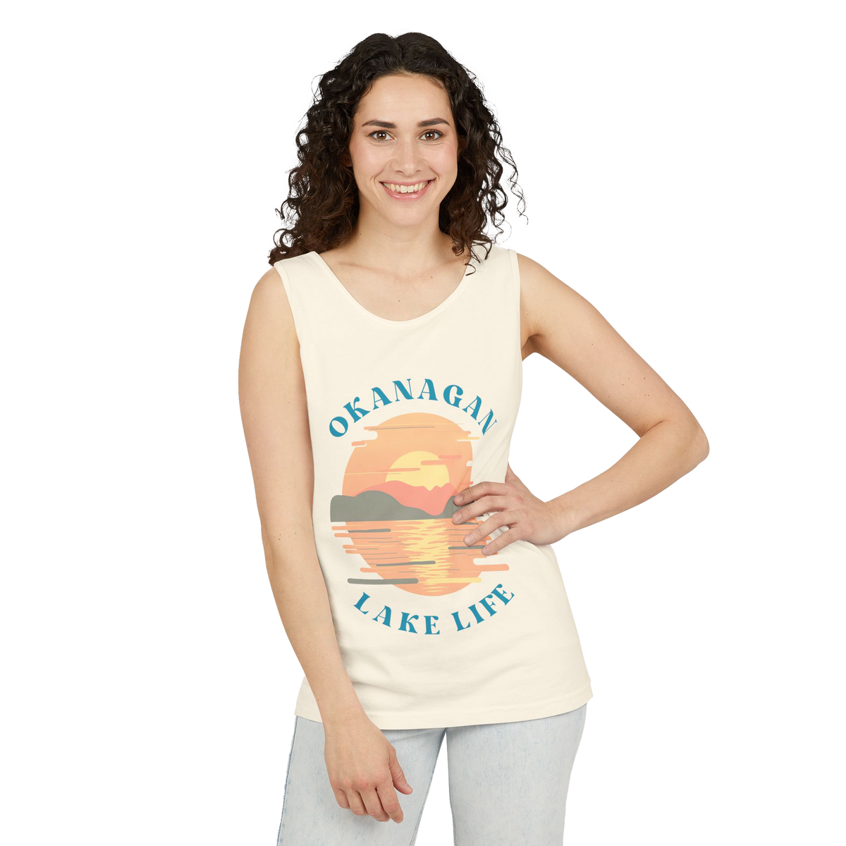 A woman modeling a sleeveless cream-colored tank top with a retro sunset graphic and the words 'OKANAGAN LAKE LIFE' printed on the front, set against a plain white background.