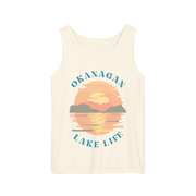 An off-white sleeveless tank top featuring a retro-style sunset graphic over a lake with the text 'OKANAGAN LAKE LIFE' in teal, displayed on a solid white background.